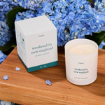 Candle and packaging labeled 'weekend in new england' , sea breeze and saltwater scented literie candle