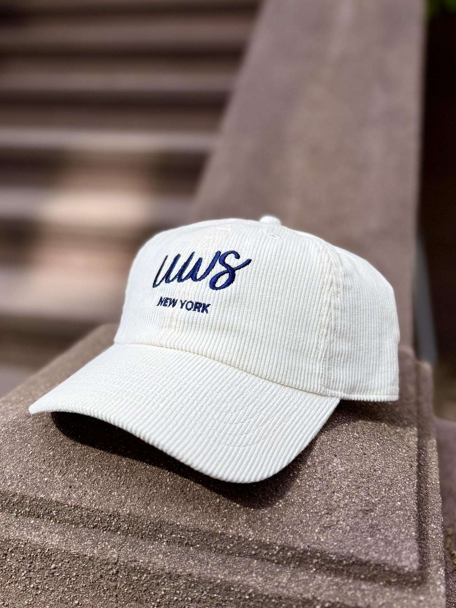 White cap with blue text that says UWS on a textured corduroy hat